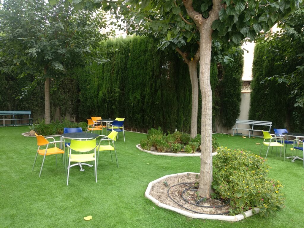Jardín verde con árboles y sillas de colores